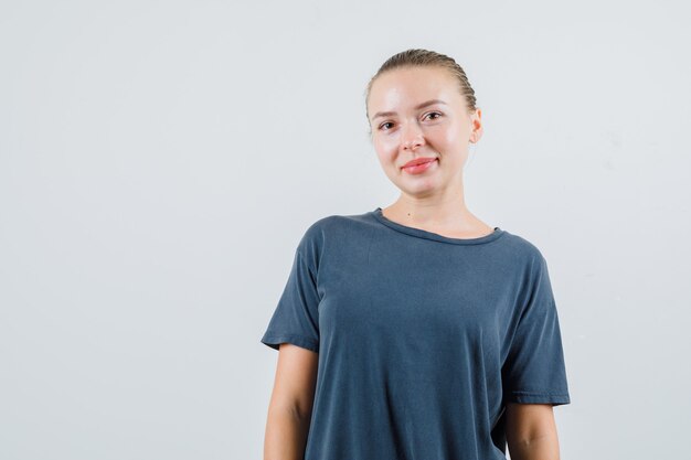 Mujer joven mirando en camiseta gris y mirando alegre