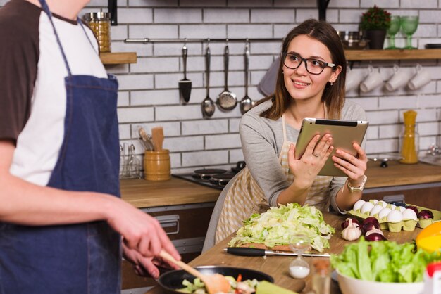 Mujer joven mirando cocinar novio