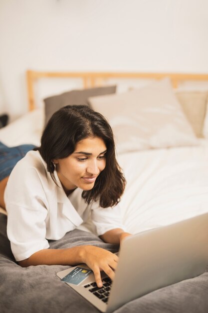 Mujer joven mirando en la computadora portátil en la cama
