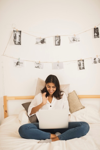 Foto gratuita mujer joven mirando en la computadora portátil en la cama