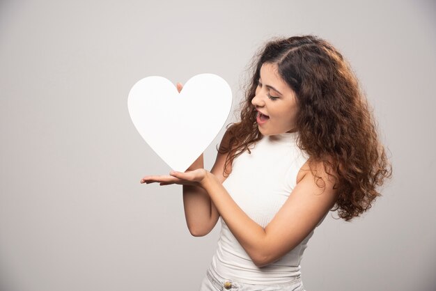 Mujer joven mirando corazón de papel hecho a mano blanco. Foto de alta calidad