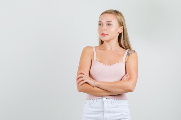 Mujer joven mirando a un lado con los brazos cruzados en camiseta, mini falda