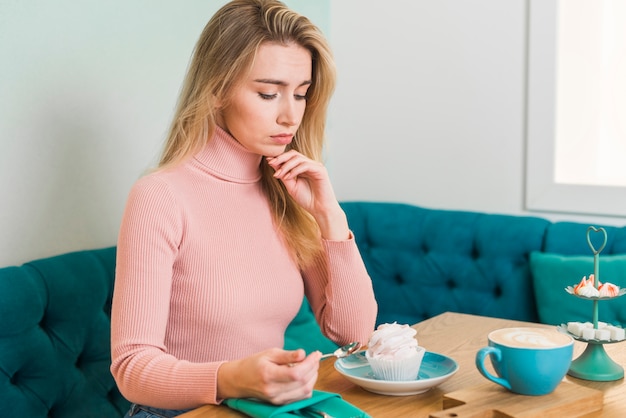 Foto gratuita mujer joven mirando merengue en la cafetería