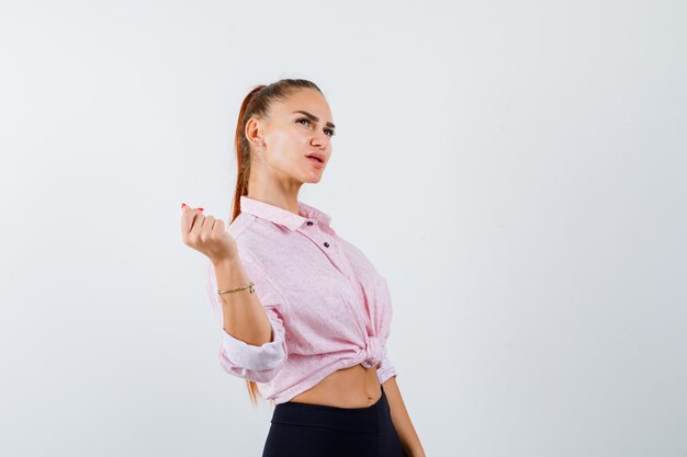 Foto gratuita mujer joven mirando a otro lado mientras está de pie en camisa casual, pantalones y mirando confiado, vista frontal.