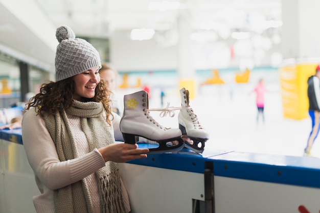 Foto gratuita mujer joven mirando y patines de hielo