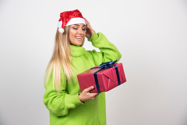 Mujer joven mirando un regalo de Navidad festivo.