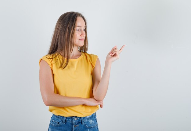 Mujer joven, mirar hacia el lado, y, señalar lejos, en, camiseta