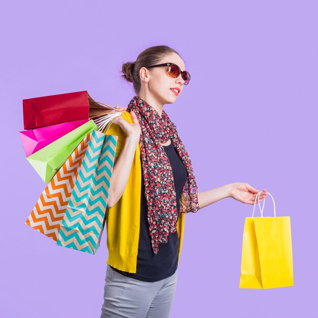 Mujer joven de moda con el bolso de compras sobre fondo púrpura