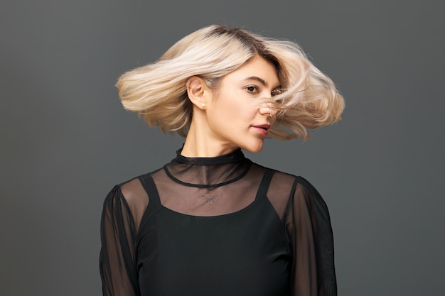 mujer joven de moda con peinado bob y anillo en la nariz disfrutando de la música con los ojos cerrados, sonriendo, divirtiéndose en la fiesta, dando la vuelta, con el pelo al viento. Vacaciones y ambiente festivo