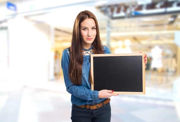 Foto gratuita mujer joven de moda que muestra un tablero negro