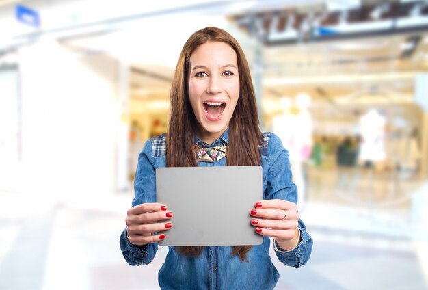 Mujer joven de moda que parece sorprendido y sosteniendo una tarjeta gris