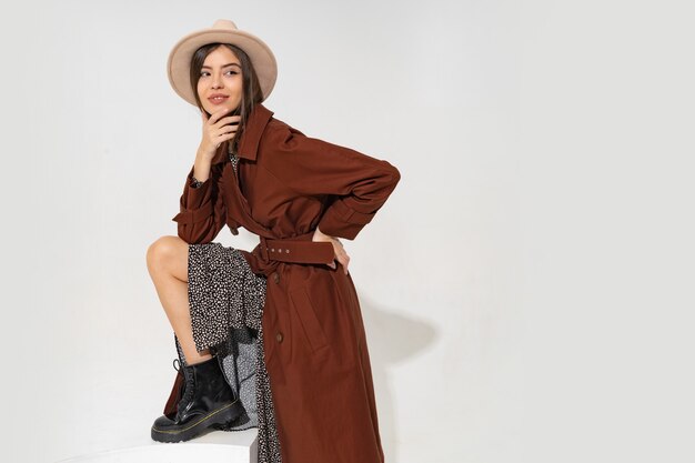 Mujer joven de moda con sombrero y abrigo de invierno de moda posando