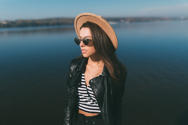 Mujer joven modelo chica posando en día de otoño en la orilla del lago vestida con ropa casual