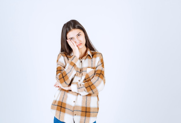 Mujer joven molesta de pie sobre la pared blanca.