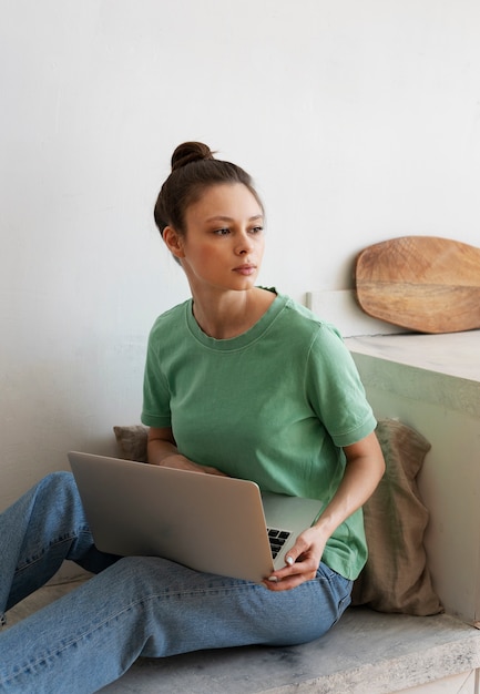 Mujer joven con moño desordenado trabajando desde casa