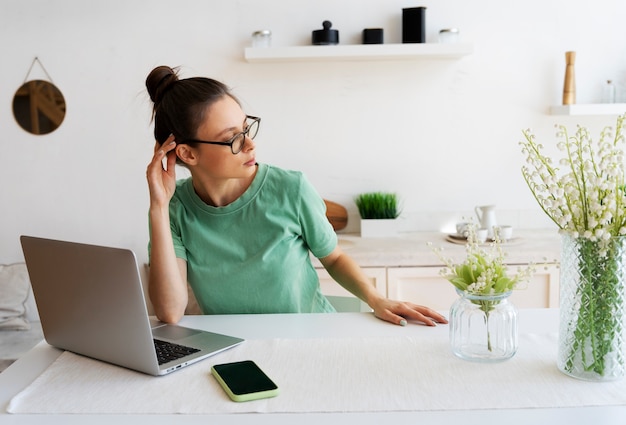 Mujer joven con moño desordenado trabajando desde casa