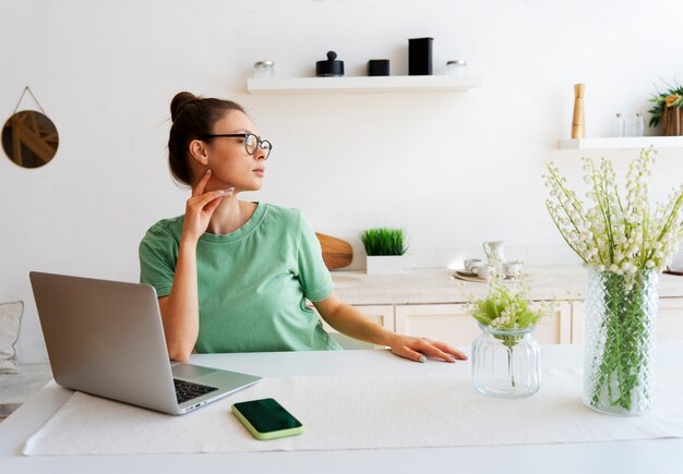 Mujer joven con moño desordenado trabajando desde casa