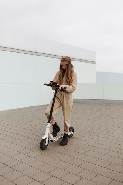 Foto gratuita mujer joven montando un scooter eléctrico