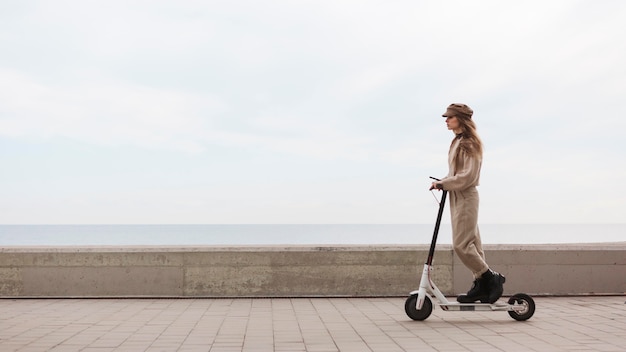 Foto gratuita mujer joven montando un scooter eléctrico