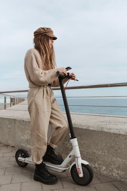 Foto gratuita mujer joven montando un scooter eléctrico