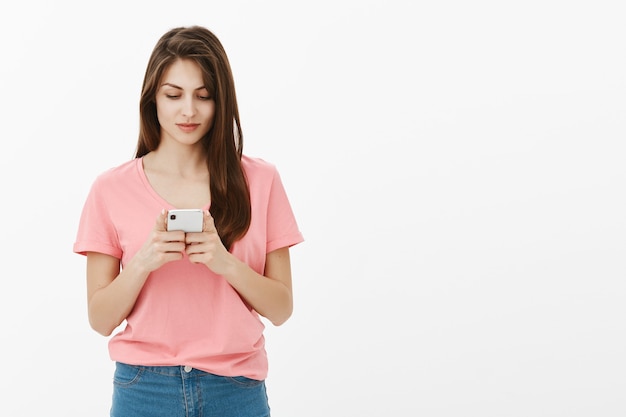 Mujer joven morena posando en el estudio con su teléfono