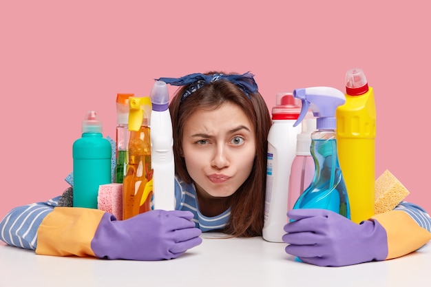 Mujer joven morena sentada junto a productos de limpieza