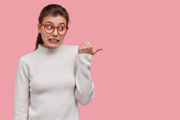 Mujer joven morena en suéter blanco y gafas rojas