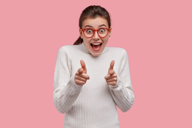 Mujer joven morena vestida con suéter blanco y gafas rojas