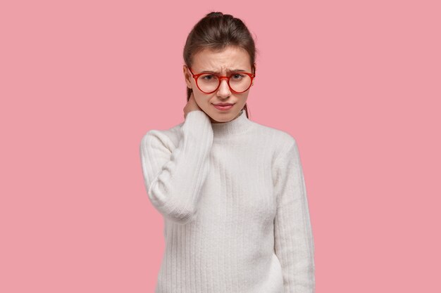 Mujer joven morena vestida con suéter blanco y gafas rojas