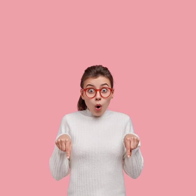 Mujer joven morena vestida con suéter blanco y gafas rojas