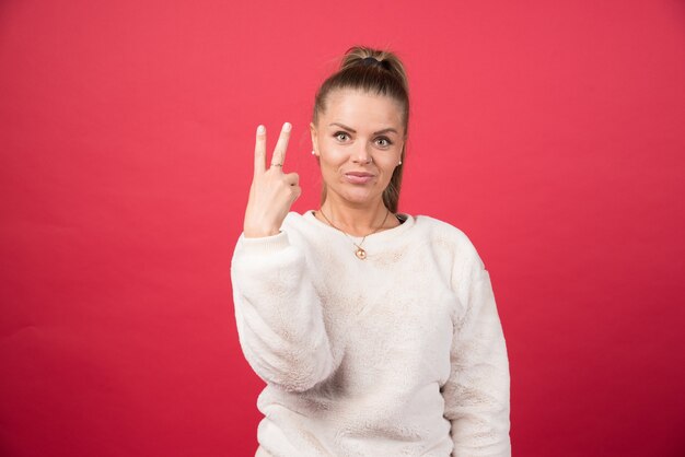 Mujer joven mostrando los dedos haciendo el signo de la victoria