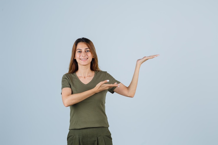 Foto gratuito mujer joven mostrando gesto de bienvenida en camiseta, pantalón y mirando feliz, vista frontal.