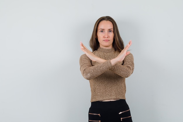 Foto gratuita mujer joven mostrando gesto cerrado en blusa dorada