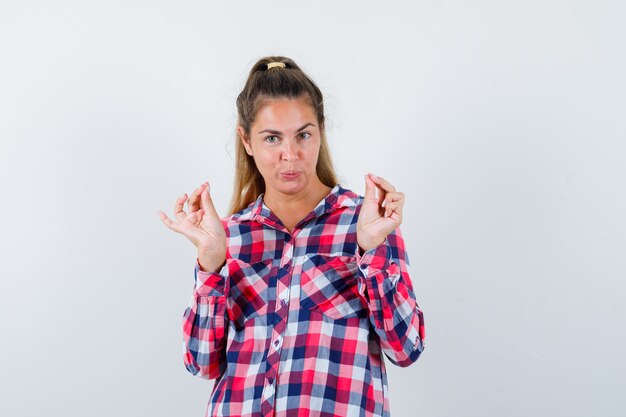 Foto gratuita mujer joven mostrando gesto de dinero en camisa casual y mirando sensible, vista frontal.