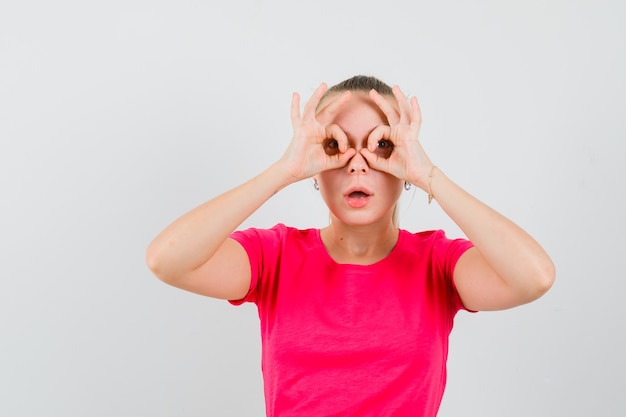 Mujer joven mostrando gesto de gafas en camiseta y mirando enfocado