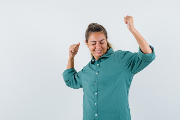 Mujer joven mostrando gesto de ganador en blusa verde y luciendo lindo