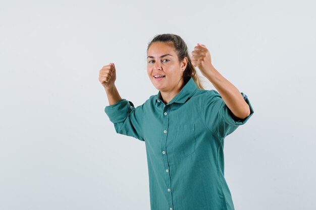 Mujer joven mostrando gesto de ganador en camisa azul y mirando confiado