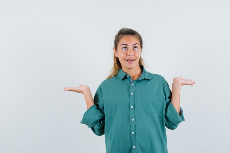 Foto gratuito mujer joven mostrando gesto de impotencia en camisa azul y mirando confundido