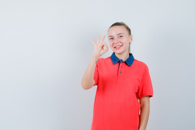 Mujer joven mostrando gesto ok en camiseta y mirando alegre