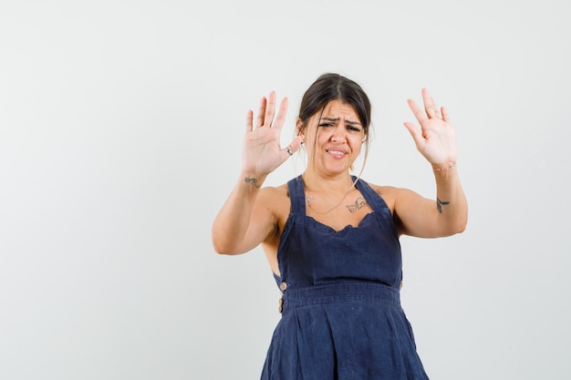 Foto gratuita mujer joven mostrando gesto de rechazo en vestido y mirando molesto