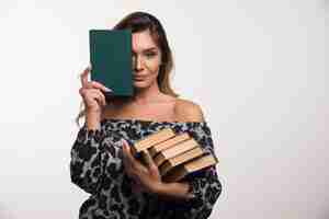 Foto gratuita mujer joven mostrando libros en la pared blanca.