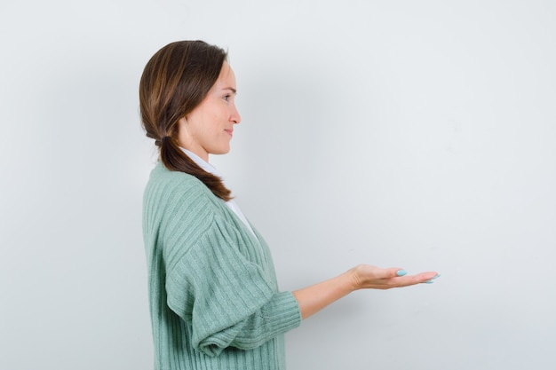 Foto gratuita mujer joven mostrando o presentando algo en la pared blanca con espacio de copia