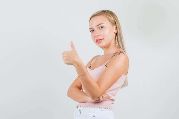 Mujer joven mostrando el pulgar hacia arriba y sonriendo en camiseta