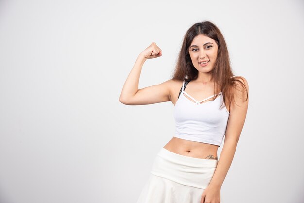 Mujer joven mostrando su brazo de fuerza femenina e independiente.