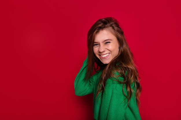 Mujer joven muy encantadora bailando en la pared roja en traje de invierno