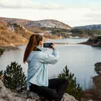 Foto gratuita mujer joven en la naturaleza tomando fotos