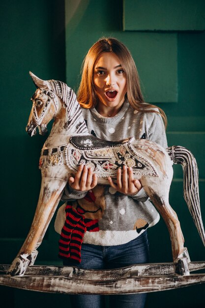 Mujer joven en Navidad con silla de pony de madera