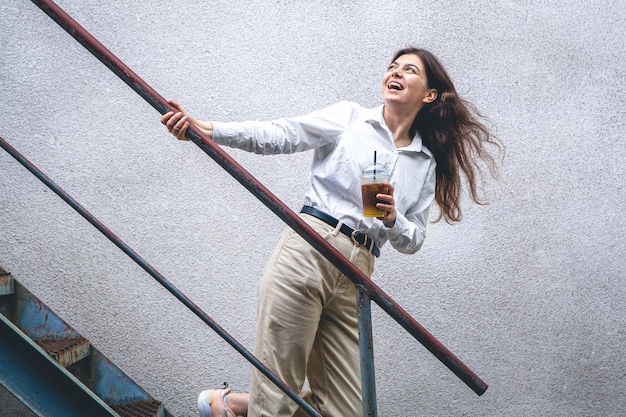 Foto gratuita mujer joven de negocios cerca de las escaleras con una taza de café