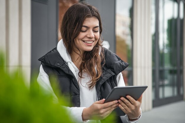 Mujer joven de negocios con una tableta en el fondo del edificio