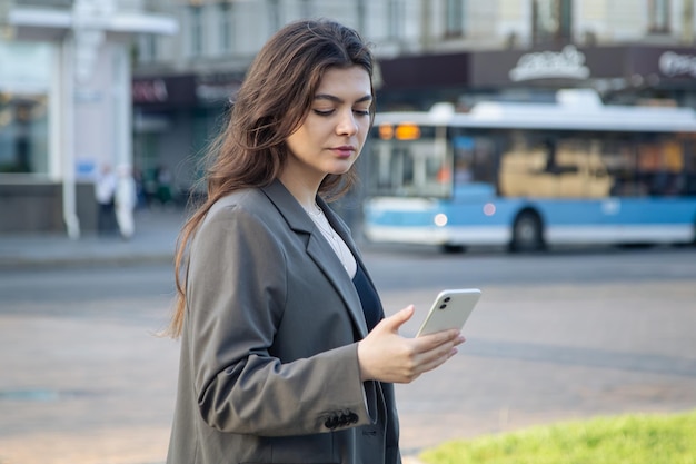 Mujer joven de negocios con un teléfono inteligente en un fondo borroso de la ciudad